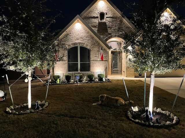 Exterior accent lighting on trees and brick facade of a San Antonio home